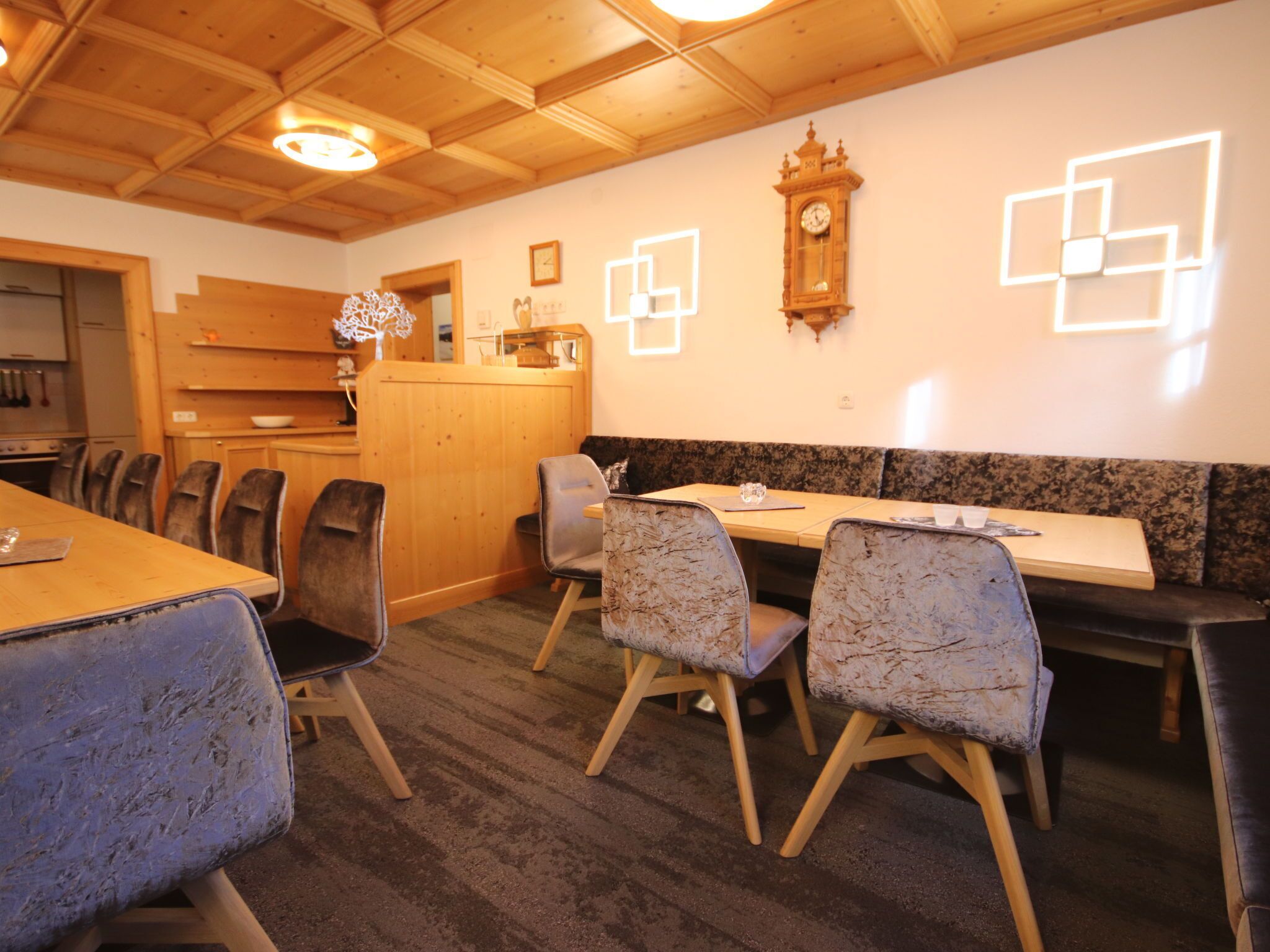 Un espace repas avec des tables et des chaises en bois, une horloge au mur et un plafond en bois.