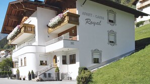 En vit byggnad med balkonger och en skylt med texten ”APART – GARNI Royal”.