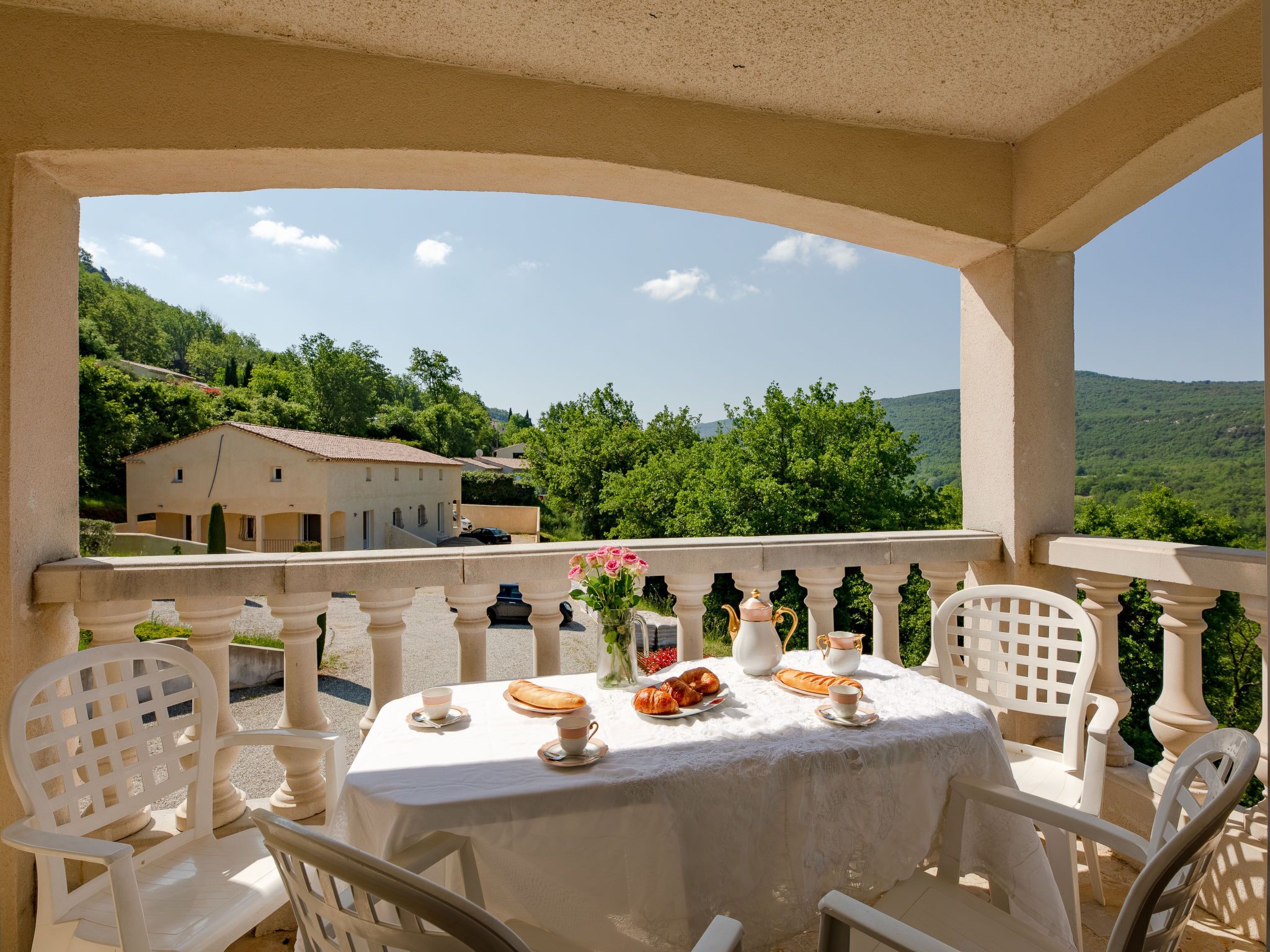 Un balcón con una mesa dispuesta para el desayuno, con vistas a una colina pintoresca.