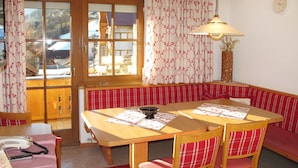 A dining area with a wooden table, red and white checkered chairs, and a bench.