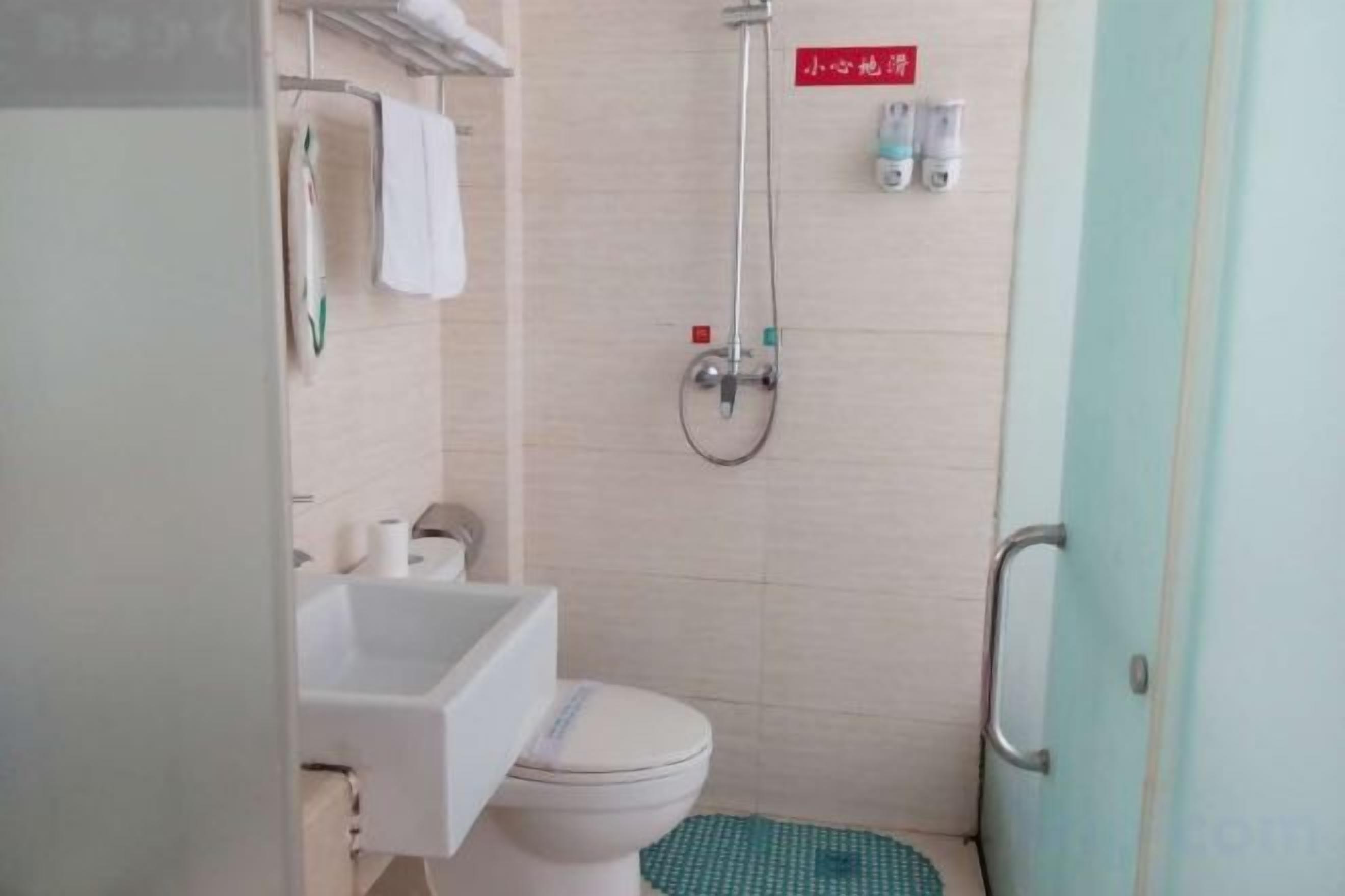 A compact bathroom with a toilet, sink, and shower.