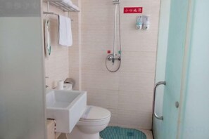 A compact bathroom with a toilet, sink, and shower. - Wo'ermei Hotel (Enshi City)