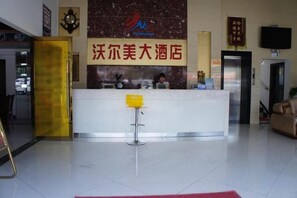 A hotel reception area with a reception desk, a seating area, and a television screen. - Wo'ermei Hotel (Enshi City)