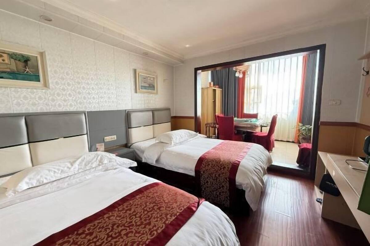 Una habitación de hotel con dos camas, un escritorio, una silla y un espejo grande.
