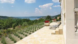 A stone pathway leading to outdoor seating with a view of a coastal landscape.