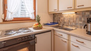 Een keuken met een Siemens gasfornuis, een spoelbak en een raam met witte gordijnen.