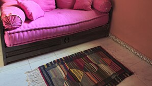 A pink sofa with decorative pillows, a patterned rug, and a wooden cabinet with intricate carvings. - Riad Sleeps 2 with Rooftop Views (Marrakesh)