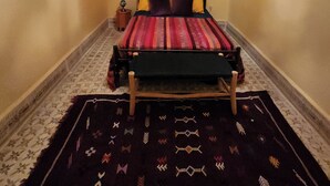 A room with a bed, a small wooden stool, and a patterned rug. - Riad Sleeps 2 with Rooftop Views (Marrakesh)