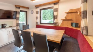 Een moderne keuken met een houten tafel, zwarte stoelen en een rode bank.