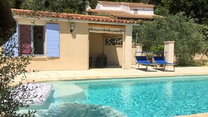 A pool area with a clear blue pool, lounge chairs, and a building with a tiled roof. - Sweet Home in Luberon by Interhome (Villelaure)