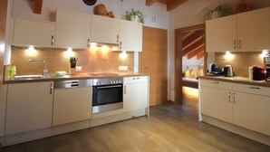 A modern kitchen with wooden beams, stainless steel appliances, and a view into a bedroom. - Bergblick by Interhome (Kappl)