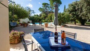 Eine Terrass mit Tisch, Stühlen und einem Pool im Hintergrund.