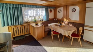 Ett kompakt kök med en matplats, ett fönster med gardiner och en klocka på väggen.