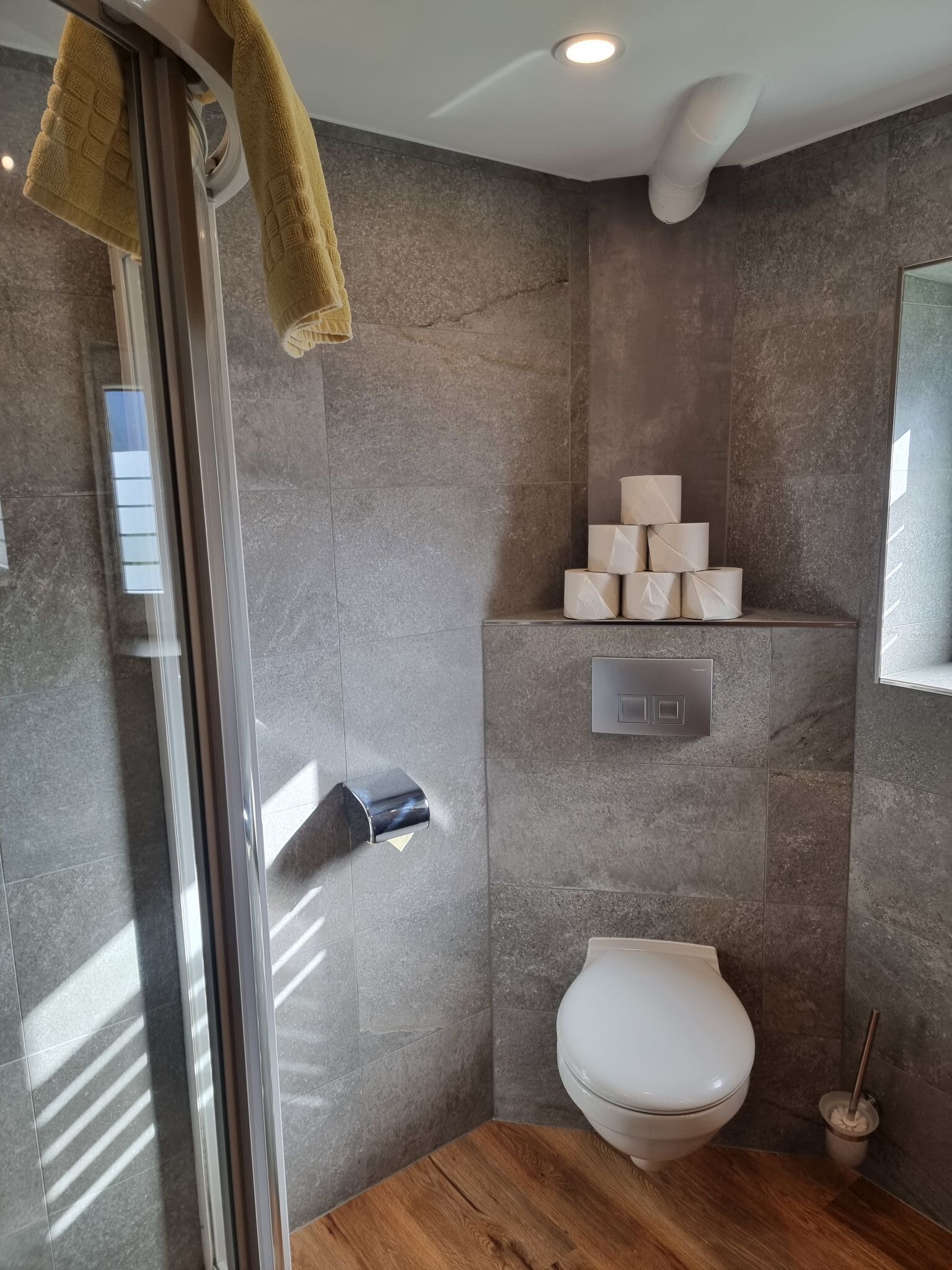 Et badeværelse med glasbrugedør, toilet og vask.