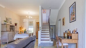 Un vaste espace de vie comprenant un canapé en cuir, une table à manger et un escalier menant à un autre niveau.