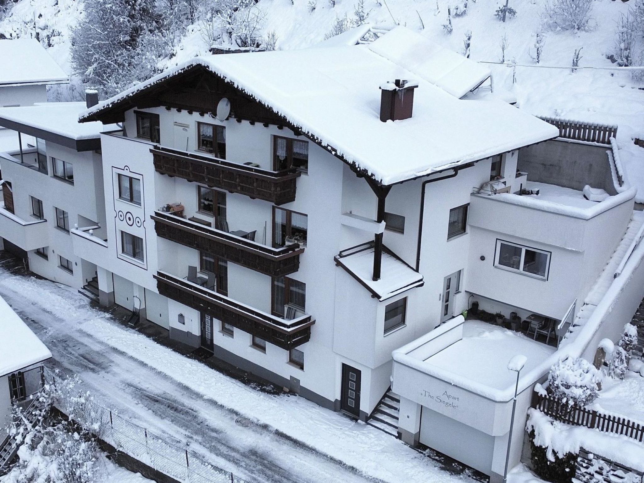 A multi-story building with balconies and a snow-covered roof.
