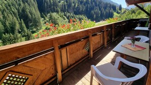 Een houten terras met uitzicht op een bebost berglandschap.