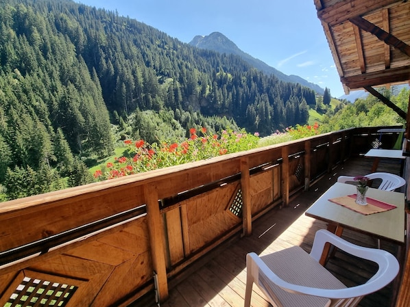 A wooden deck with a view of a forested mountain range.