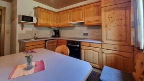 Een keuken met houten kastjes, een magnetron, een koffiezetapparaat en een spoelbak.