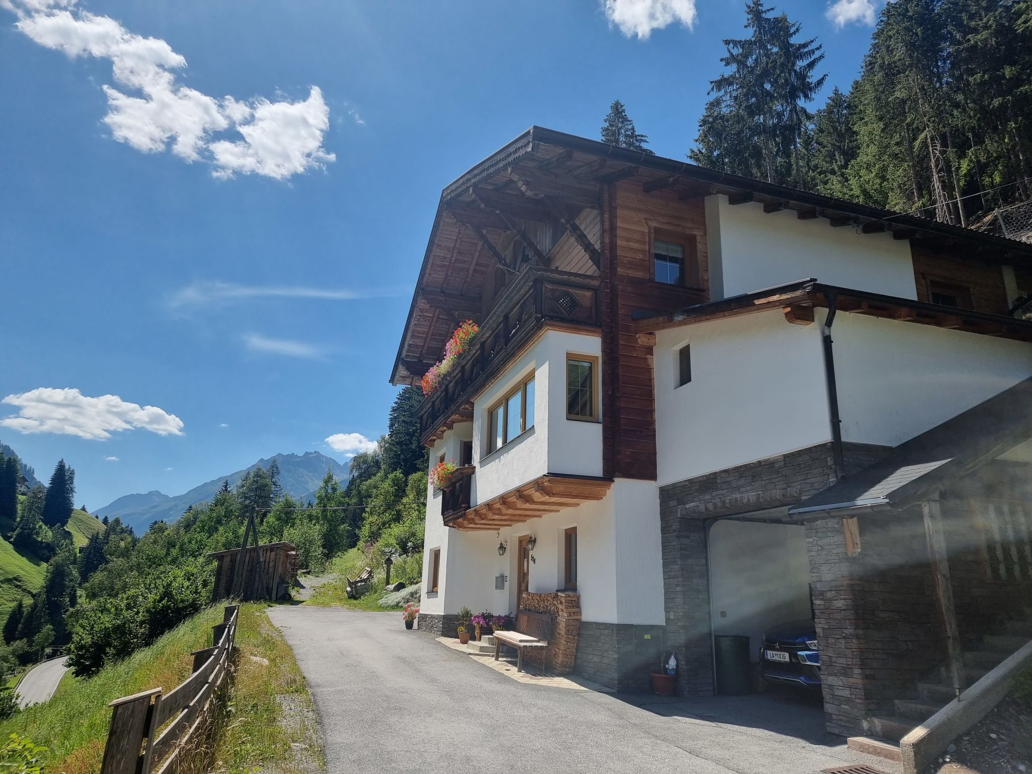 A two-story chalet with a stone facade, wooden balcony, and a garage.