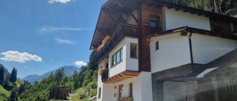 A two-story chalet with a stone facade, wooden balcony, and a garage.