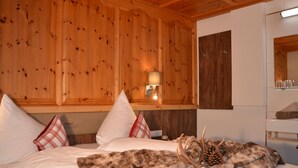 A bed with white linens, a fur throw, and a pine cone decoration. - Wechner by Interhome (Kappl)