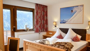 A wooden bed with a mountain view, a window with curtains, a lamp, and a chair. - Wechner by Interhome (Kappl)