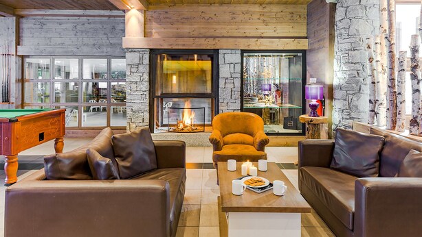 A cozy lounge area with leather sofas, a billiards table, and a fireplace.