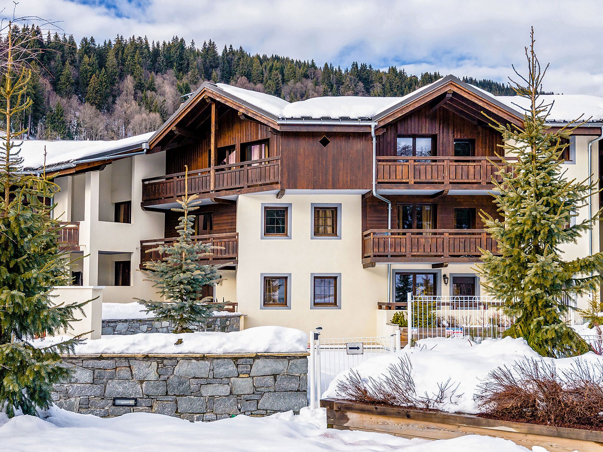 Un edificio de madera de varios pisos con balcones, rodeado de nieve en el suelo y árboles.