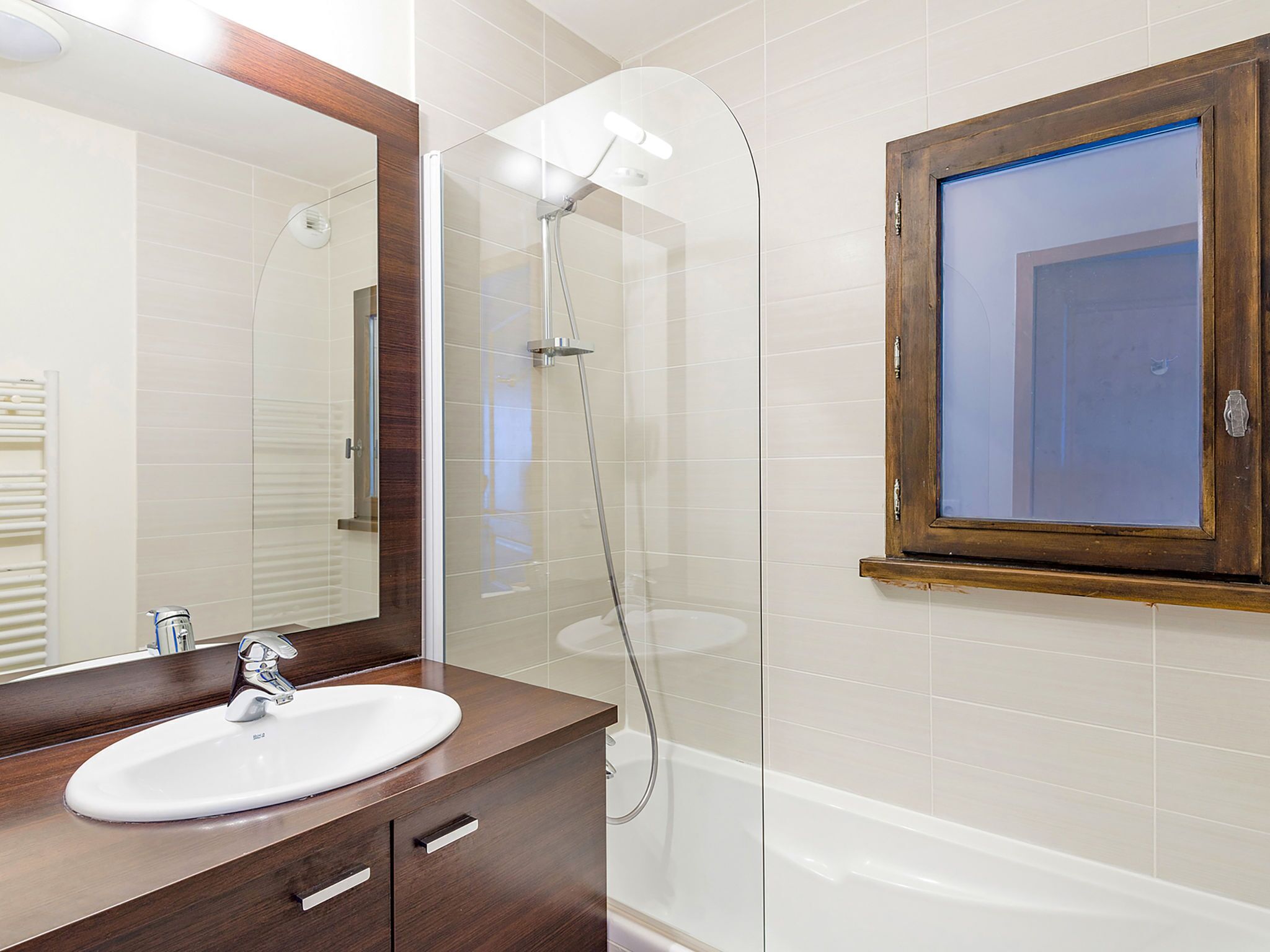 A bathroom with a white sink, a mirror, and a shower enclosure.