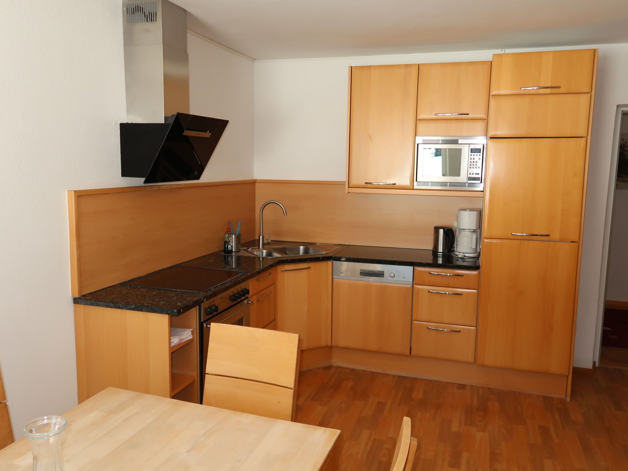 A compact kitchen with wooden cabinets, a microwave, a coffee maker, and a dishwasher.