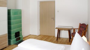 Ein Zimmer mit einem Bett, einem Sessel, einem kleinen Tisch und einer Tür.