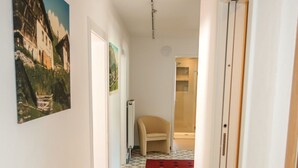 A hallway with patterned floor tiles, a beige chair, and a door leading to a bathroom. - Altes Zollhaus by Interhome (Nauders)