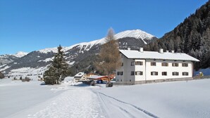 Paisagem coberta de neve com um edifício com várias janelas e telhado coberto de neve.
