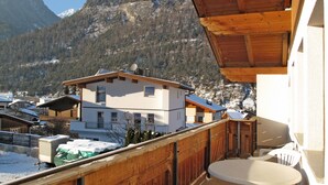 A balcony with a wooden railing overlooking a mountainous area with snow-covered houses. - Apartment Köhle by Interhome (Pfunds-Samnaun)