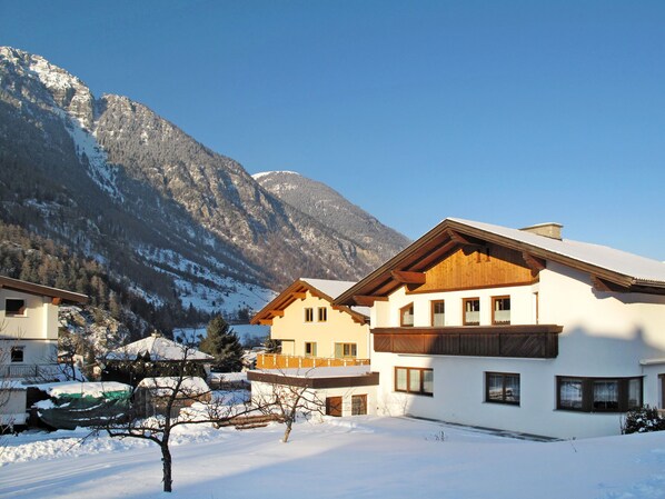 A snow-covered mountain village with traditional wooden houses and a clear view of the mountains.