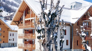 Una cabaña de madera con balcones, rodeada de montañas nevadas.