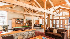 Un lodge acogedor con mesa de billar, mobiliario de madera y una pared de piedra.