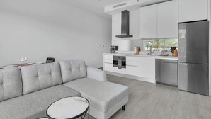A modern kitchen with white cabinets, a stainless steel refrigerator, and a built-in oven. - Modern 1BR | Pool & BBQ | Steps to 7 Mile Beach (Grand Cayman)