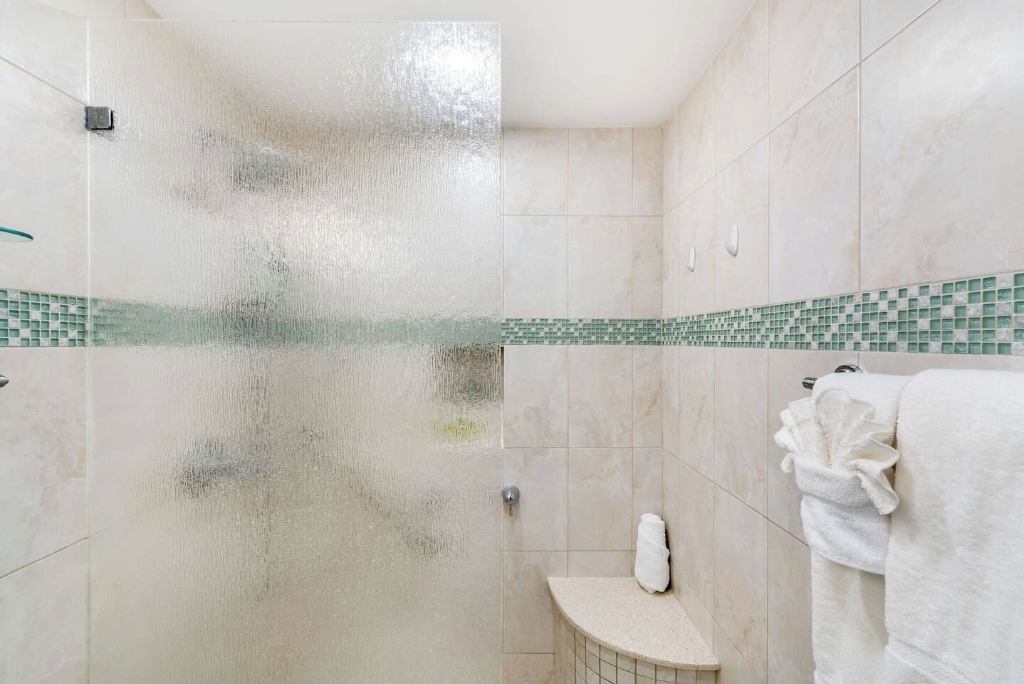 A bathroom with a glass shower door, a small sink, and a towel rack.