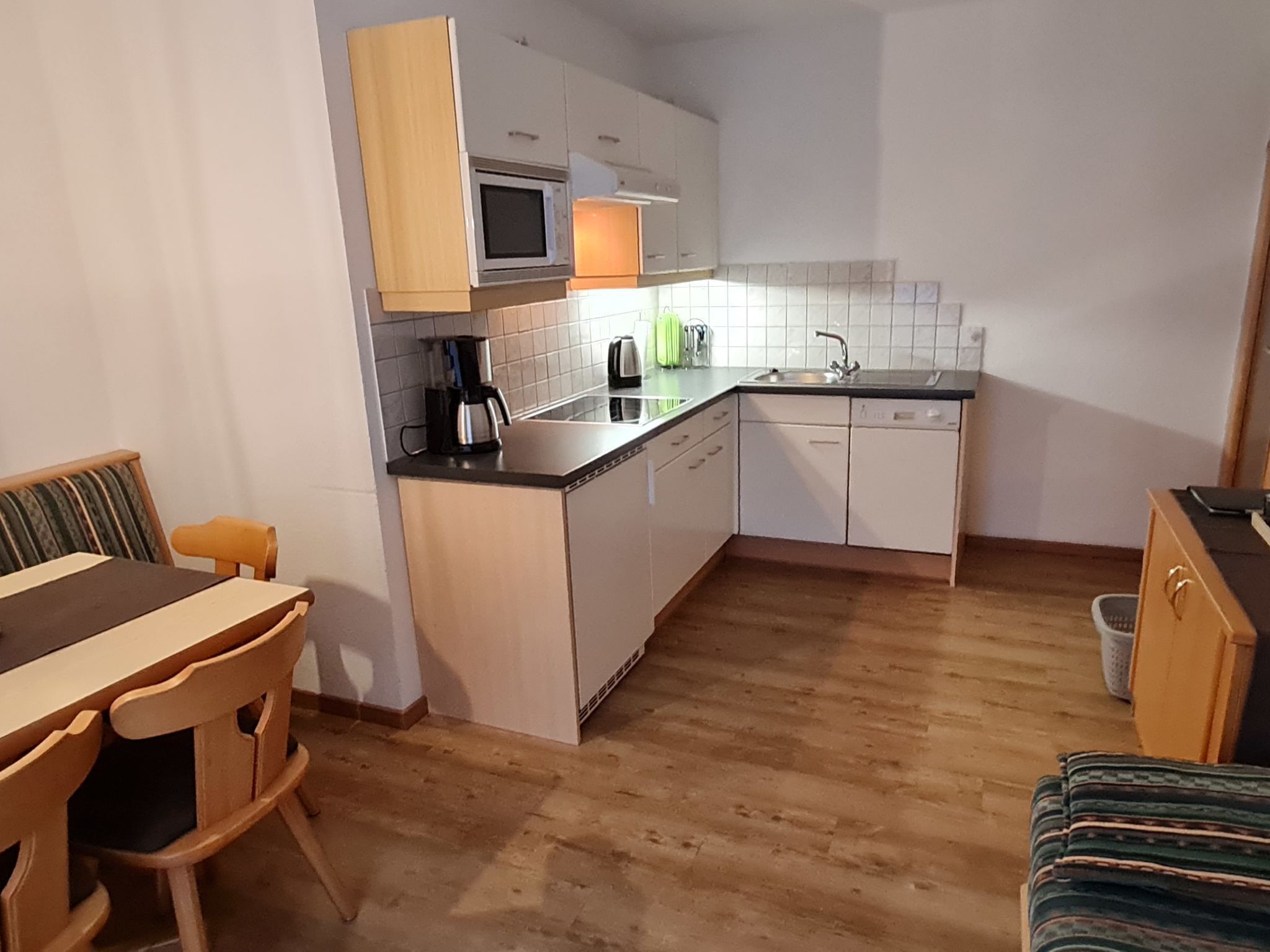 Una cucina compatta con mobili bianchi, un forno a microonde, una macchina da caffè e un lavandino.