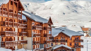 A wooden chalet-style building with multiple balconies and a ski slope in the background. - Les Hauts de Comborciere by Interhome (La Toussuire)