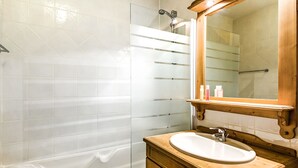 Un baño moderno con bañera, tocador de madera con lavamanos y un espejo grande.