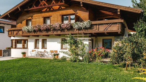 A traditional wooden chalet with a balcony adorned with flowers, a well-maintained garden, and a clear sky. - Apart Grazia by Interhome (Prutz/Kaunertal)