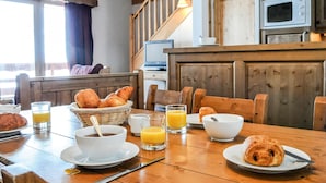 Ein Frühstückstisch mit Brot, Kaffee und Orangensaft auf einer Holztischplatte.