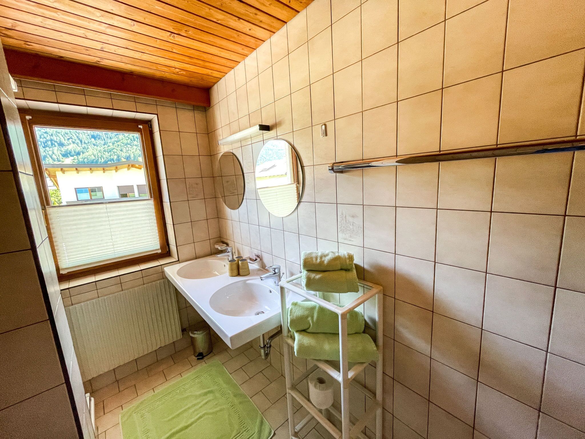 A bathroom with a window, a sink, a mirror, and a towel rack.