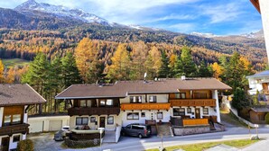 A traditional chalet-style building with a sloped roof, a wooden balcony, and a view of a forested mountain range. - Rosi Studio by Interhome (Sölden)