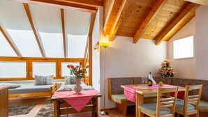 A cozy, well-lit room with a wooden ceiling, a dining table with chairs, a bench, and a sofa. - Rosi Studio by Interhome (Sölden)