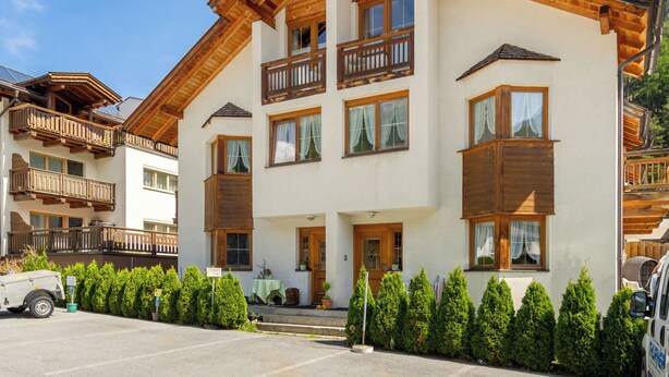 A multi-story hotel with wooden balconies and a parking area. - Rosi Studio by Interhome (Sölden)