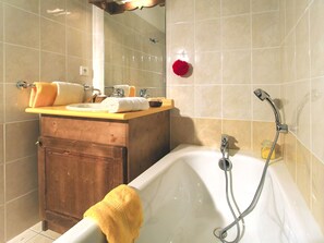 Bathroom features a bathtub, vanity with mirror, and tiled walls.